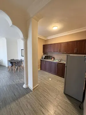 an empty kitchen with a refrigerator and a table at Warm 1BR in Dabouq in Amman