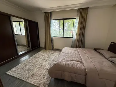 a bedroom with a large bed and two windows at Warm 1BR in Dabouq in Amman