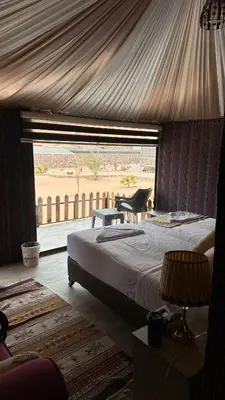a bedroom with a large bed and a large window at Moon Dunes Wadi Rum in Disah