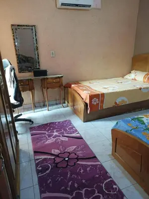 a room with two beds and a table and a rug at ام النعمان شليت in Umm as Surab