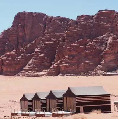 a row of huts in the desert near a mountain at Wadi Rum Camp and Tours in Wadi Rum