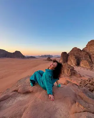 a woman laying on a rock in the desert at Kadi Wadi Rum in Al Jafr