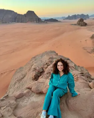 a woman sitting on a rock in the desert at Kadi Wadi Rum in Al Jafr