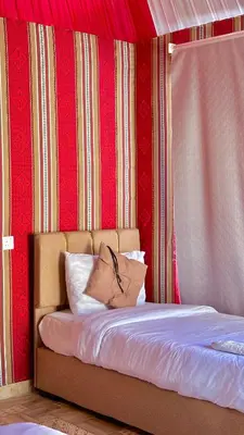 a bed in a room with a red wall at wadi rum luxury bubble soul in Wadi Rum