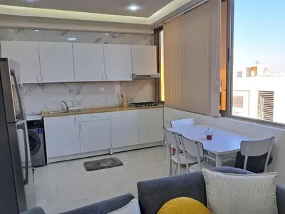 a kitchen with white cabinets and a table with chairs at منزل السعادة in Amman