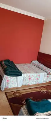 two beds in a room with a red wall at المنشيه هاوس in Maţār al Malik Ḩusayn