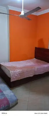 two beds in a room with an orange wall at المنشيه هاوس in Maţār al Malik Ḩusayn