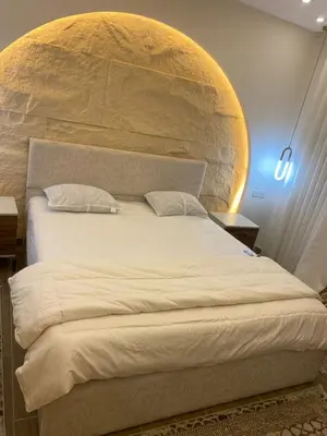a bedroom with a large bed with a stone wall at Sanad Apartment شقة فندقية in Aqaba