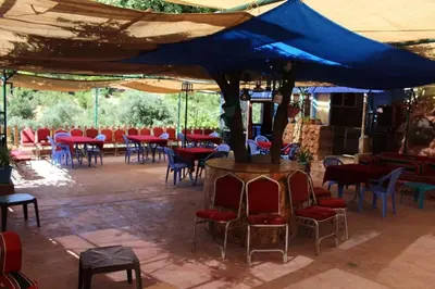a tent with chairs and tables under a blue umbrella at استراحة ومنتجع قرية الزرب in Ajloun