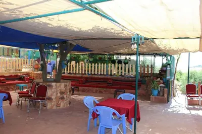 a table and chairs under a tent with a table and a bench at استراحة ومنتجع قرية الزرب in Ajloun
