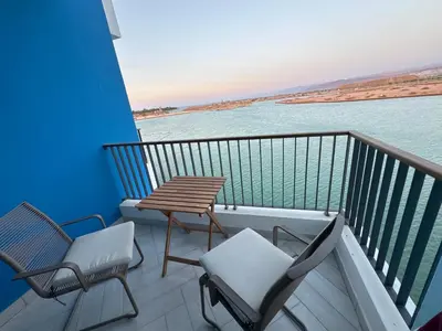 two chairs and a table on a balcony with the water at Ayla Aqaba Azure 2 bedroom in Aqaba