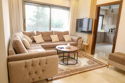 a living room with a couch and a table at Rams Der Ghbar 3BR cozy Apt in Amman