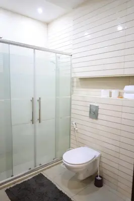 a bathroom with a toilet and a glass shower at Rams Der Ghbar 3BR cozy Apt in Amman
