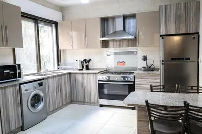 a kitchen with a stove and a dishwasher at Rams Der Ghbar 3BR cozy Apt in Amman