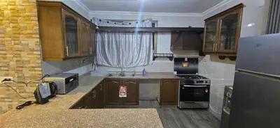 a small kitchen with wooden cabinets and a refrigerator at الريان in Amman