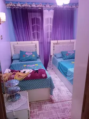 two beds in a room with purple curtains at ام جوزه هاوس in Umm Jawzah