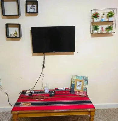 a tv on a wall with a table with a tv at Petra Triclinium Home in Wadi Musa