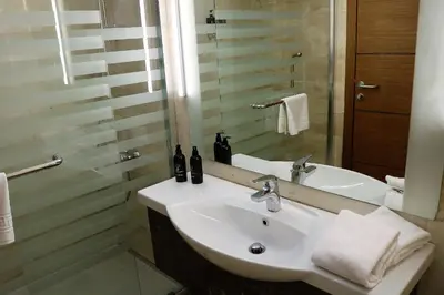 a bathroom with a white sink and a shower at Olive Tree Amman in Amman