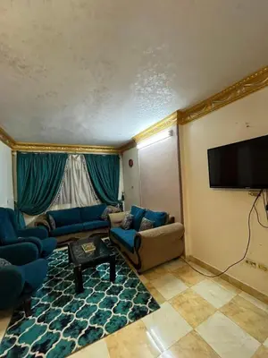 a living room with blue furniture and a flat screen tv at سونا موتل in Sūf