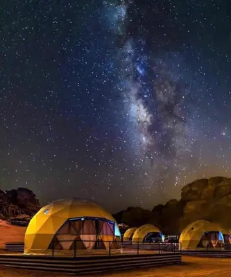 a group of tents under a starry sky at Wadi Rum Sand Camp in Al Jafr