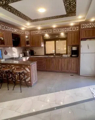 a kitchen with wooden cabinets and a white refrigerator at Janna2Villa in Shūnat Nimrīn
