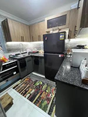 a kitchen with a black refrigerator and some food on the counter at فلورس لوج
