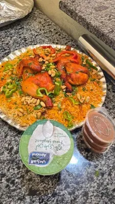 a plate of food with chicken and rice on a counter at الضليل هاوس in Abū Ghārah