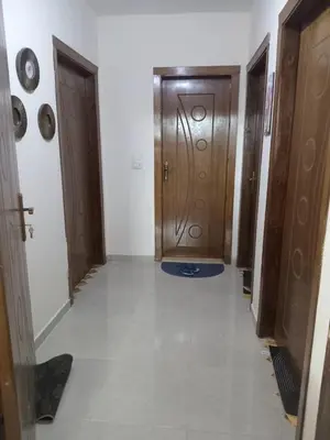 a hallway with two wooden doors and a tile floor at اللجين 6m in Irbid