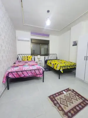 a bedroom with two beds and a rug at اللجين 6m in Irbid