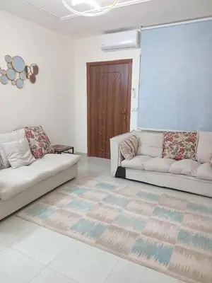 a living room with two white couches and a brown door at اللجين 6m in Irbid