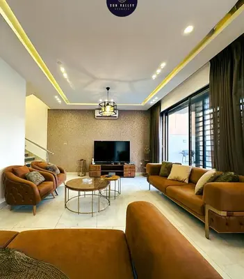 a living room with couches and a flat screen tv at SunValley in Al Rama