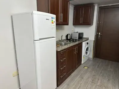 a kitchen with a white refrigerator and a washer and dryer at استوديو الجاردنز gardens studio 319 in Al Jafr