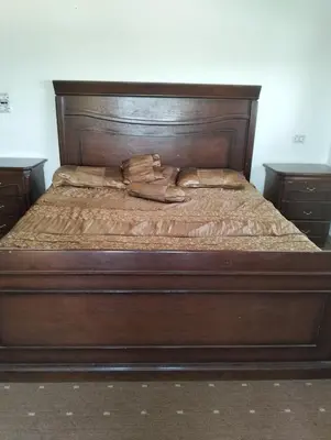 a bed with a wooden headboard with a purse on it at ام الينابيع عجلون in Ajloun