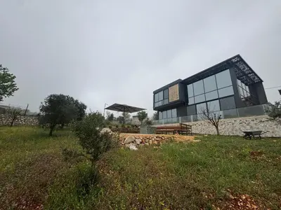 a building with glass windows and a bench in a field at AlFahed Farm in Ajloun