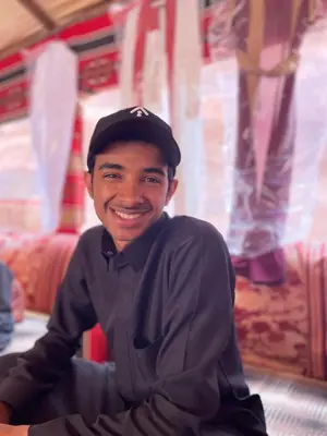 a man wearing a hat is smiling for the camera at Moon Camp in Al Jafr