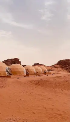 a group of domes in the desert on a dirt field at Moon Camp in Al Jafr
