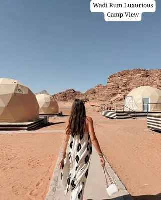 a woman in a dress walking in the desert at Wadi Rum Luxurious Camp View in Wadi Rum