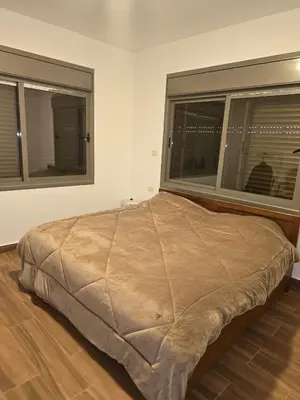 a large bed in a room with two windows at Le Jardin in Madaba