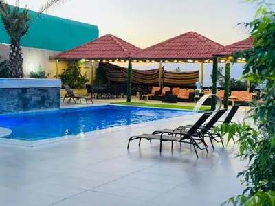 a swimming pool with lounge chairs next to a building at The Royal Chalet in Ath Thukhaynāt