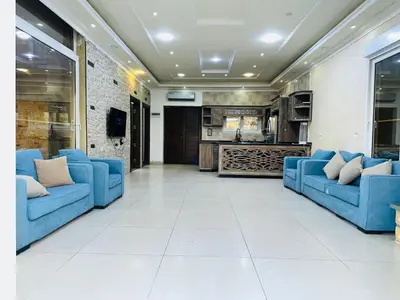 a living room with blue couches and a kitchen at The Royal Chalet in Ath Thukhaynāt