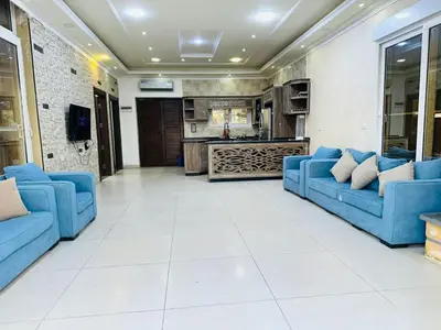 a living room with blue couches and a kitchen at The Royal Chalet in Ath Thukhaynāt