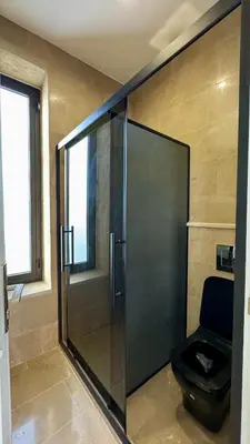 a bathroom with a glass shower with a toilet at Giving City in Amman