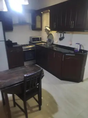 a kitchen with black cabinets and a table and a stove at Amman in Amman