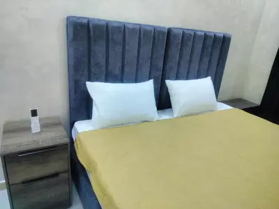 a bed with a blue headboard in a room at Ayla Furnished Apartments in Aqaba