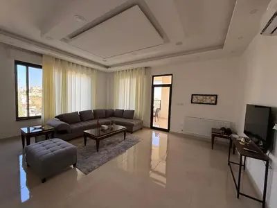 a living room with a couch and a tv at Dabouq 3BR condo in Amman