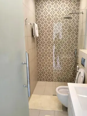 a bathroom with a shower with a toilet and a sink at Janty Apartments in Amman