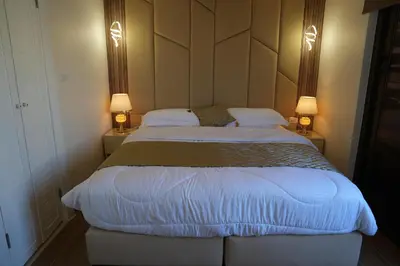 a bedroom with a large bed with two lamps at Janty Apartments in Amman