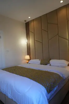 a bedroom with a large bed with a headboard at Janty Apartments in Amman
