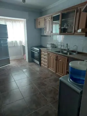 a kitchen with wooden cabinets and a tile floor at Dream Home furnished Apartment in Amman