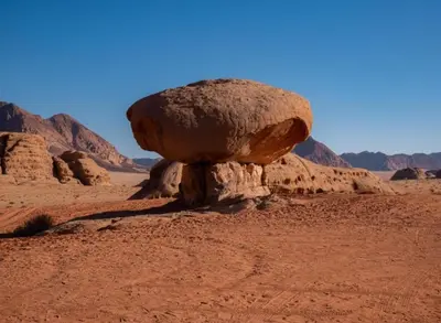 a large rock in the middle of the desert at مخيم نجوم رم in Maḩaţţat Dīsah